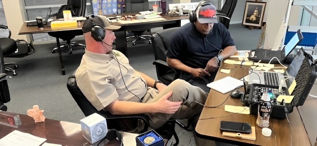 Two men sitting in a room with headphones on.
