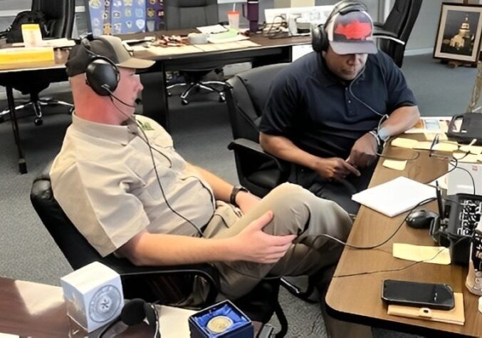 Two men sitting in a room with headphones on.